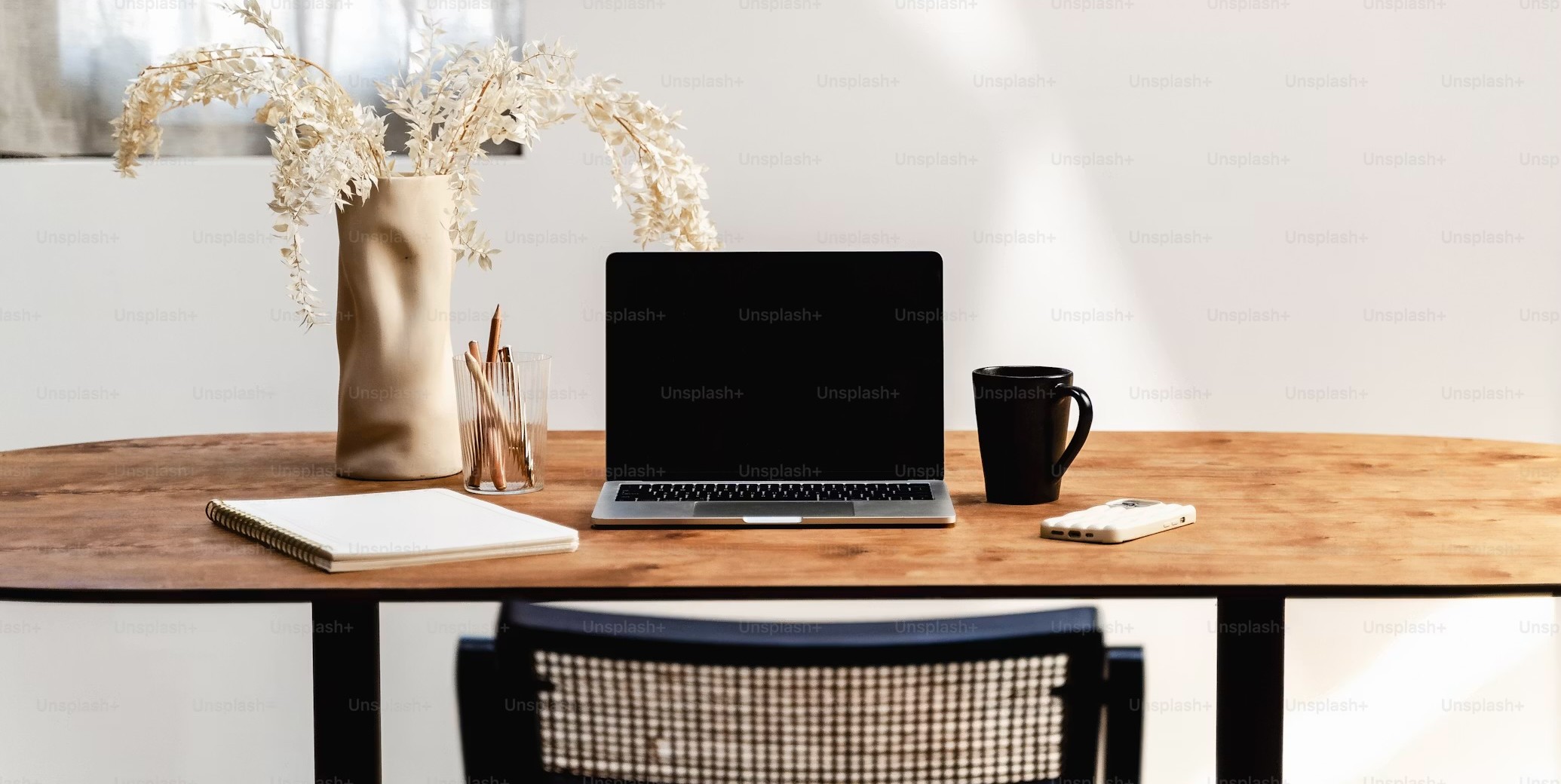 Schreibtisch mit Laptop, Notizbuch und Kaffee
